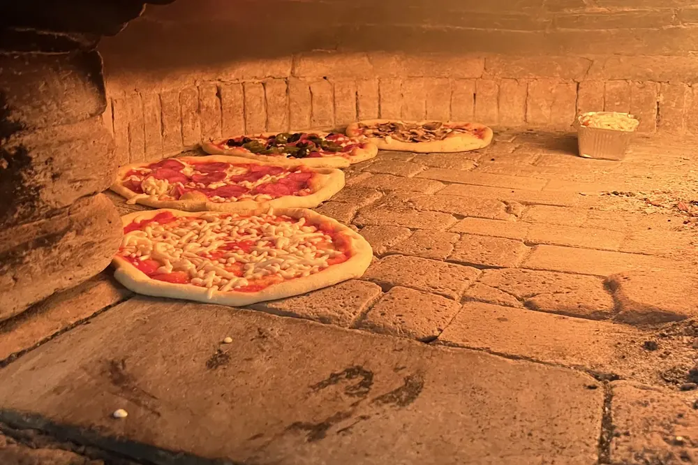 Pizzen backen auf dem Steinboden des Holzofens