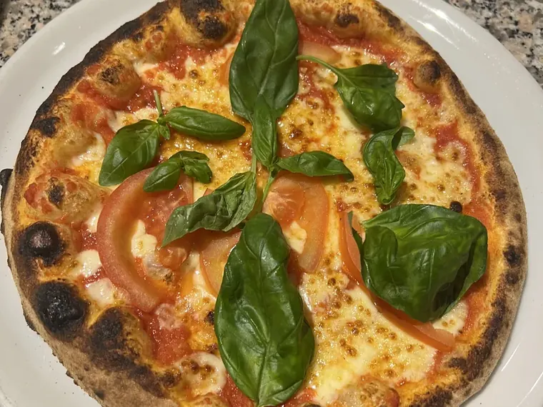 Pizza Margherita mit frischem Basilikum aus dem Holzofen