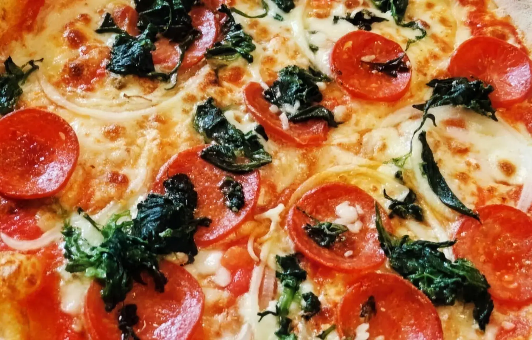 Frisch gebackene Pizza mit Salami und Spinat bei Bona Pizza in Diedelsheim