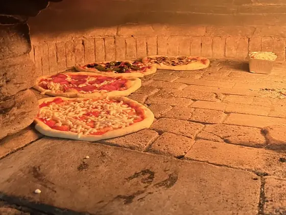 Pizzen backen auf dem Steinboden des Holzofens